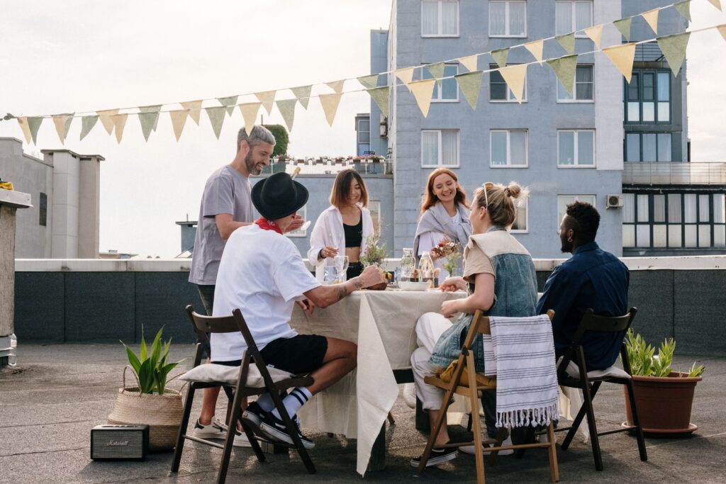A casual rooftop gathering of friends enjoying a summer day with food and drinks.